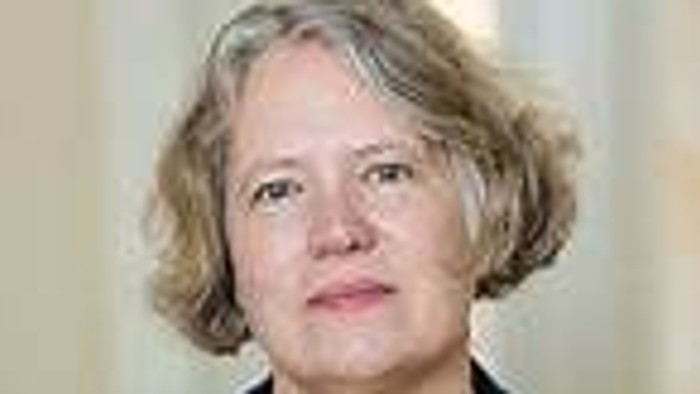 A woman with short blonde hair wearing a dark jacket.