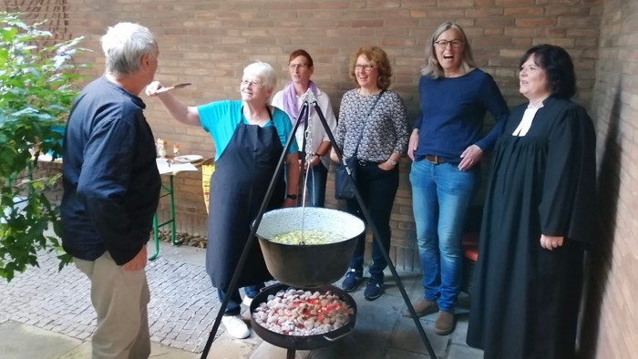 Eine Gruppe von Menschen bereitet gemeinsam Essen in einem Innenhof zu