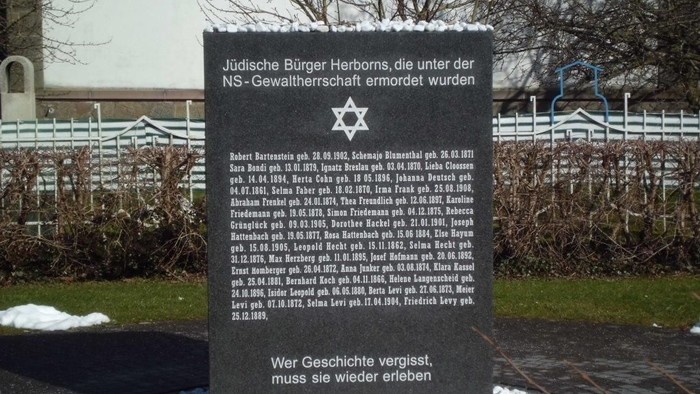 Gedenkstein für jüdische Opfer des NS-Regimes mit Liste der Namen und Inschrift "Wer Geschichte vergisst, muss sie wieder erleben"