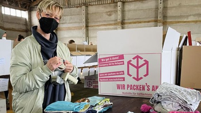 Freiwillige sortieren und verpacken Kleidung für Geflüchtete in einem Gemeinschaftsspendenzentrum.
