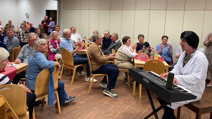 Eine Frau spielt Klavier vor einem Publikum in einem Raum.