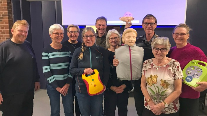 En gruppe af mennesker står sammen med gaver og blomster