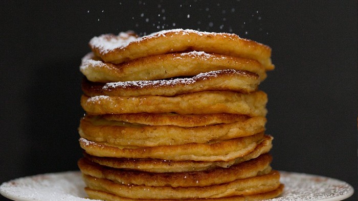 Ein Stapel goldbrauner Pfannkuchen, bestäubt mit Puderzucker