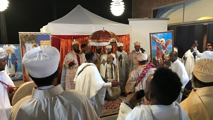 En gruppe mennesker deltager i en religiøs ceremonie under et telt.