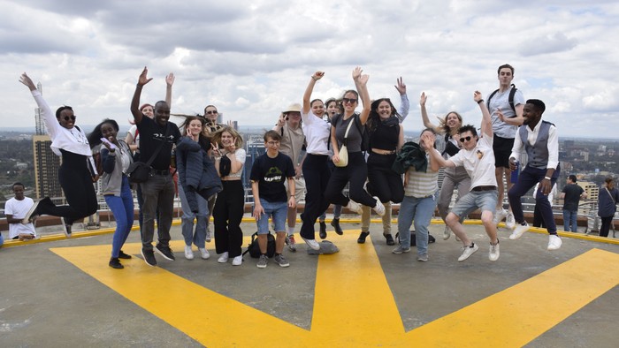 Eine Gruppe von Menschen feiert auf einem Dach mit Blick auf eine Stadt.