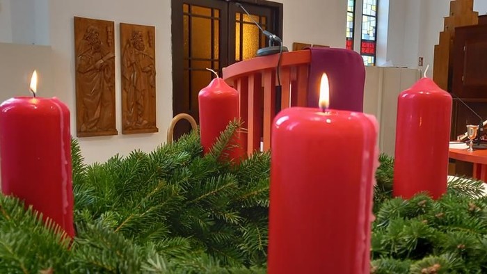 Weihnachtsdekoration mit vier brennenden Kerzen auf einem Tannengrüngebinde