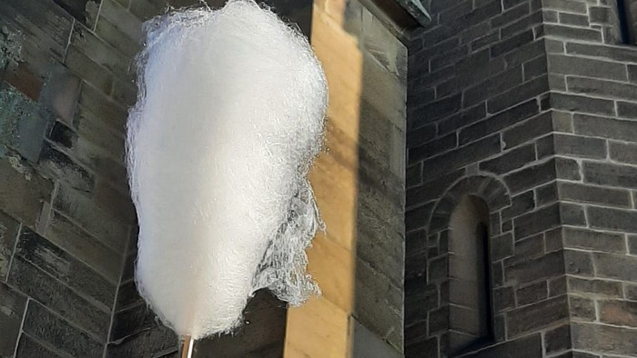 Hand hält Zuckerwatte vor Kirche