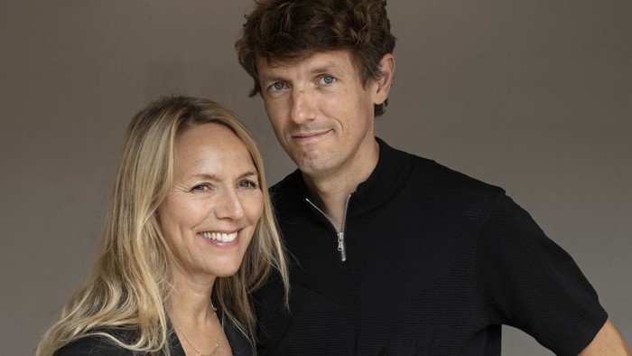 En mand og en kvinde står sammen, begge smiler og er tæt på hinanden.