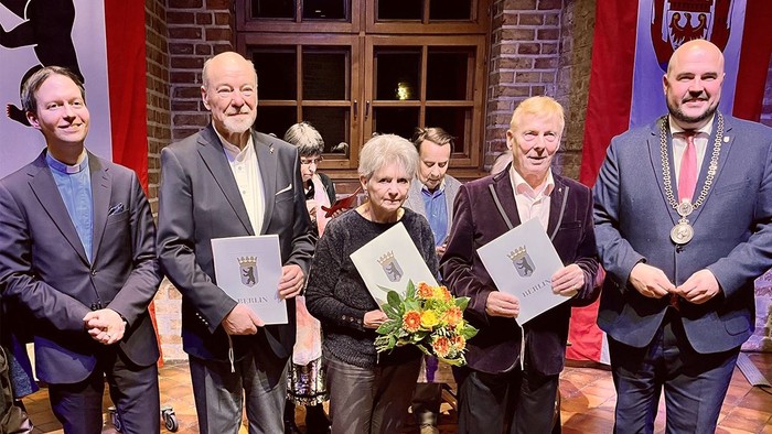 Gruppe von Menschen mit Urkunden und Blumen auf Bühne