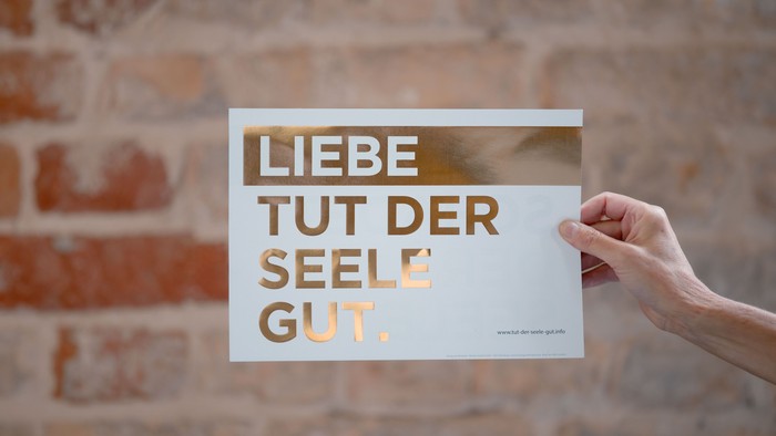Hand hält Karte mit Aufdruck "Liebe tut der Seele gut."