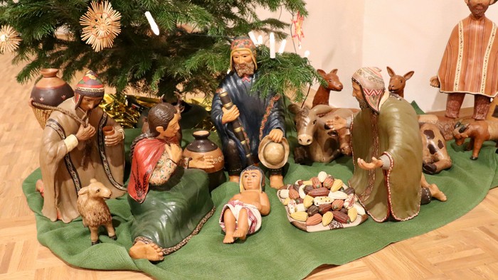 Unter dem Weihnachtsbaum stehen verschiedene Holzfiguren, darunter Tiere und Menschen, die eine Krippe darstellen.