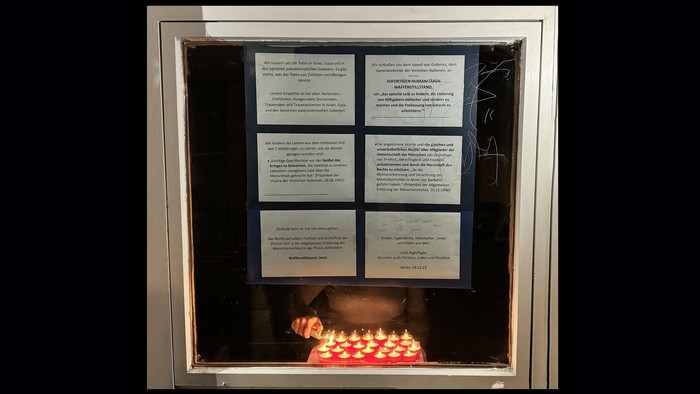 Das Bild zeigt ein Fenster mit einem Speisekartenschild und einer Kerze.