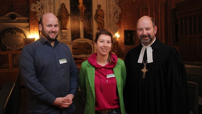 Drei Personen in Kirche posieren für Foto