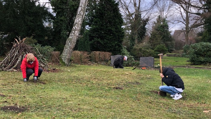 Zwei Personen graben im Garten, eine mit einem Spaten.