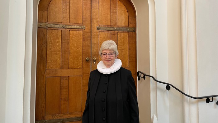 Kvinde i sort kappe og hvid skærm for døren