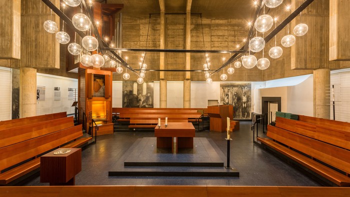 Moderne Kirche mit Holzempore und großen Kronleuchtern