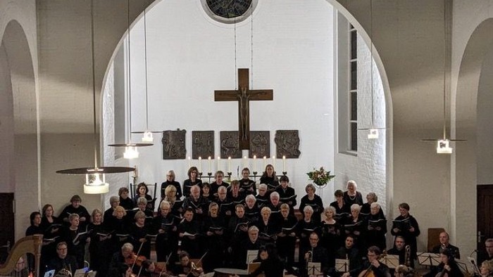 Ein Chor und Orchester proben in einer Kirche vor einem Kreuz