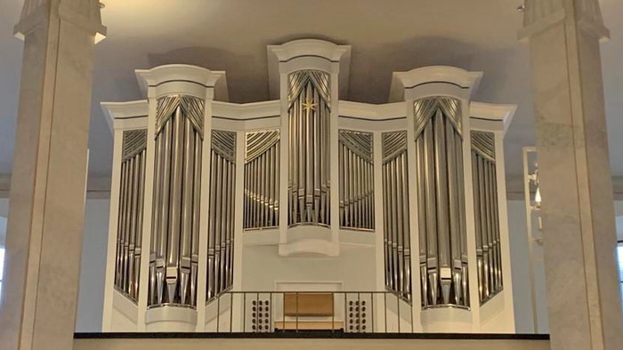 Große Orgel in einem hellen Raum mit hohen Decken und Kronleuchtern
