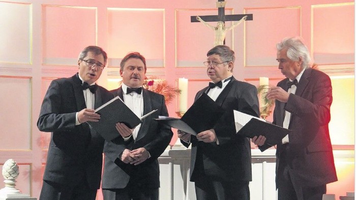 Vier Männer in Anzügen singen in einer Kirche