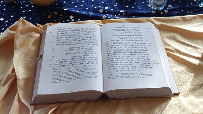 Ein Tisch mit offener Bibel, Blumen, Kreuz und Kerzen