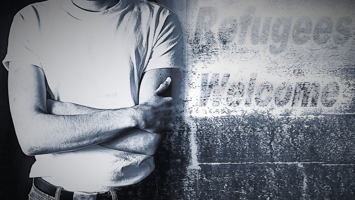 Mann mit verschränkten Armen vor Graffiti-Wand