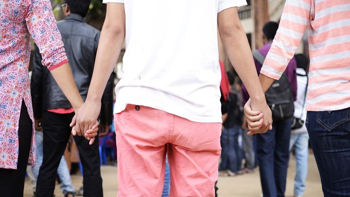 Zwei Personen gehen Hand in Hand in einer Gruppe