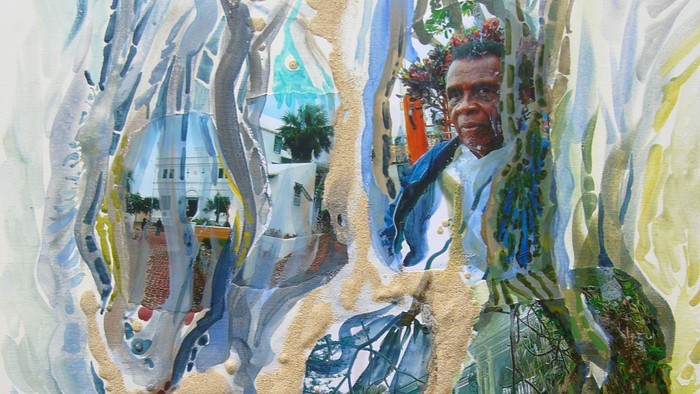 Ein Mann mit Brille steht vor einem blauen Gebäude mit Palmen und einem blauen Himmel