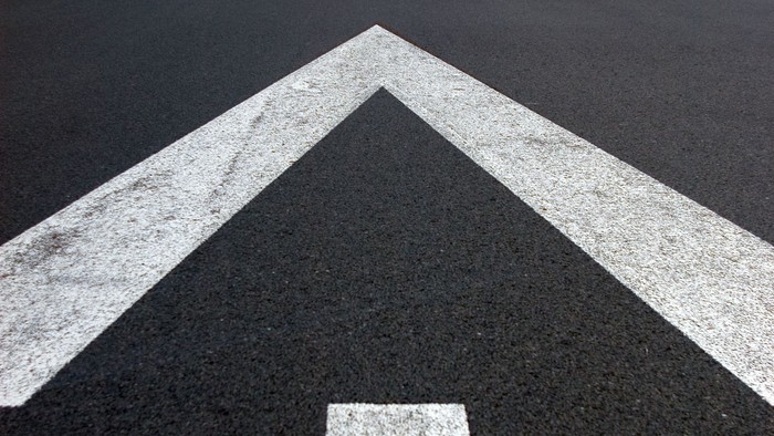 Ein schwarzer Asphaltweg mit weißer Pfeilmarkierung