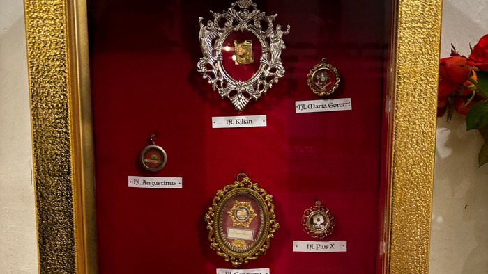 Goldgerahmte Vitrine mit religiösen Devotionalien