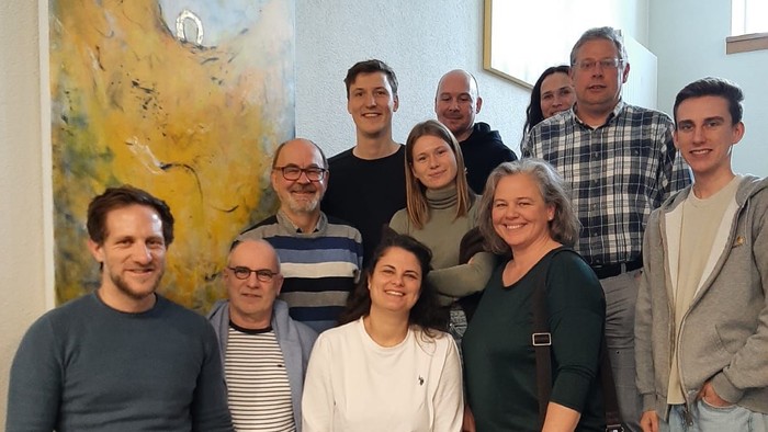 Ein Gruppe von Menschen posiert vor einem Gemälde