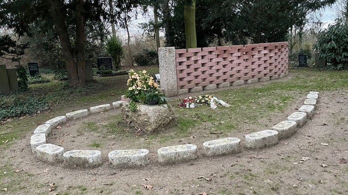 Ein kreisförmiger Steinhaufen mit Blumen in einem Park.