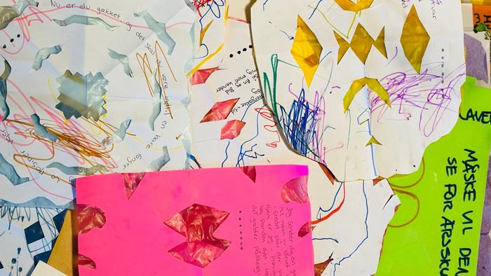 Billedet viser en samling af papir med farvede tegninger og noter.