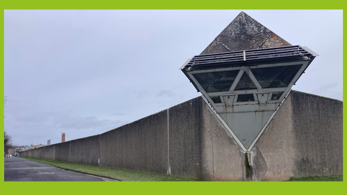 Ein modernes Gebäude mit einer dreieckigen Überdachung und einem hohen Betonmauer.