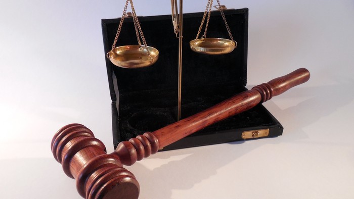 Das Bild zeigt ein Richterhammer und eine Waage, Symbole für Gerechtigkeit und Recht.