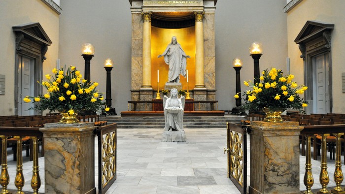 En kirkeinterior med alter, statuer og blomsterarrangements