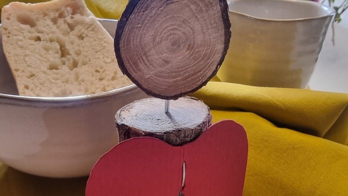 Holzschnitzerei auf gelbem Tischtuch mit Brot und Topfpflanze