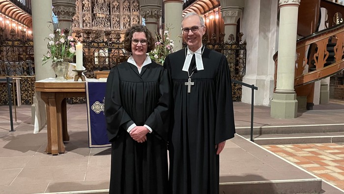 Zwei Personen in Soutanen stehen in einer Kirche