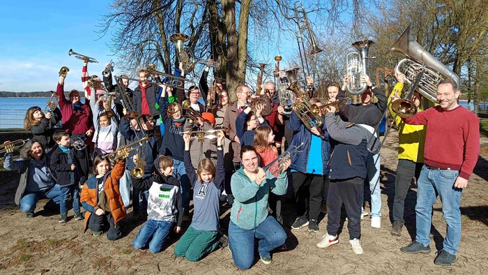 Eine große Gruppe von Menschen posiert mit Musikinstrumenten im Freien