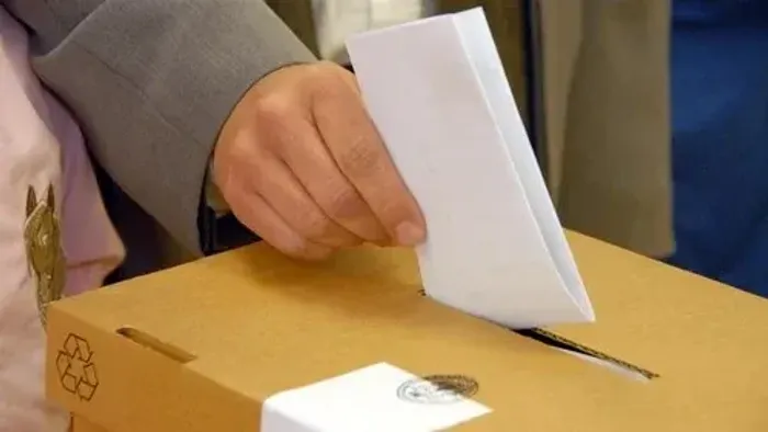 Person wirft Brief in Wahlurne.