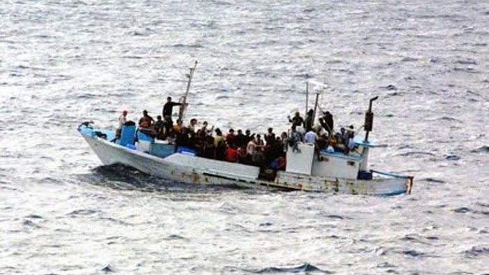 Ein überfülltes Boot mit vielen Menschen auf offener See.