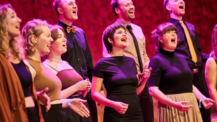 Eine Gruppe von Menschen singt auf einer Bühne