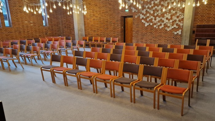 Stor hall med mange røde stolene og hængende lys.