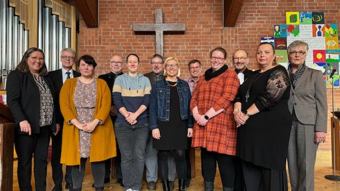 Eine Gruppe von Menschen steht in einer Kirche vor einem Kreuz
