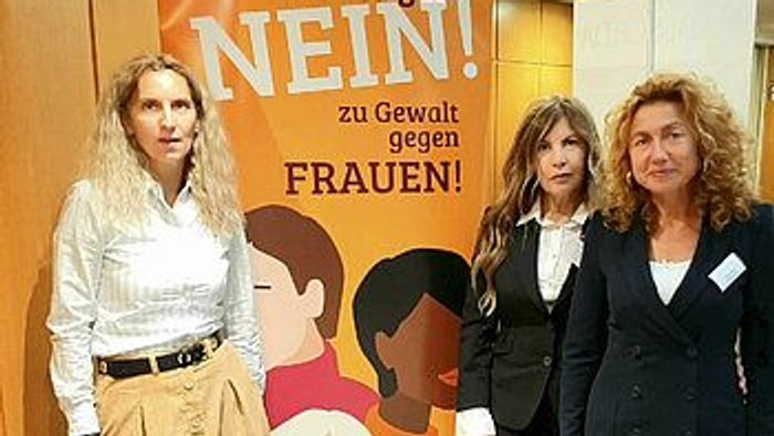 Drei Frauen stehen vor einem Plakat mit der Aufschrift "Wir sind NEIN! Zu Gewalt gegen Frauen!"