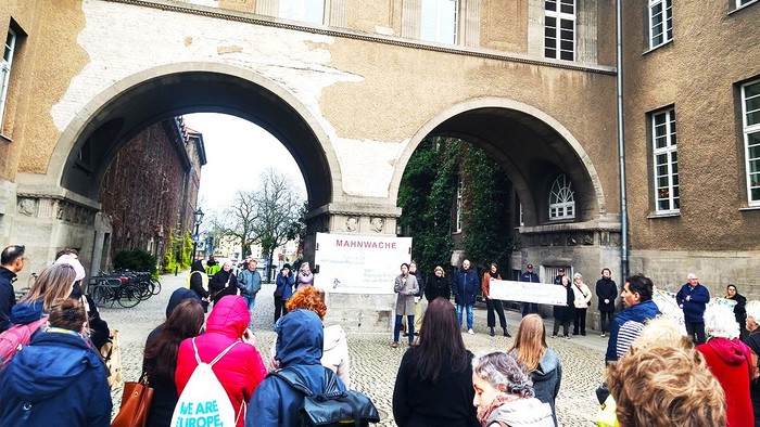 Eine Gruppe von Menschen versammelt sich vor einem großen Torbogen.