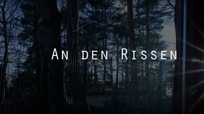 Ein dunkler Wald bei Nacht mit dem Text "An den Rissen" in der Mitte.