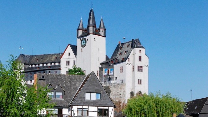 Ein Schloss mit Uhrturm und Brücke über einem Fluss