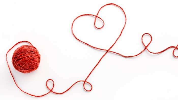 En rød tråd spoled og en hjerteformet trådsling.