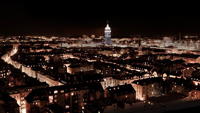 Stadt bei Nacht mit beleuchteten Häusern und einem hohen Turm