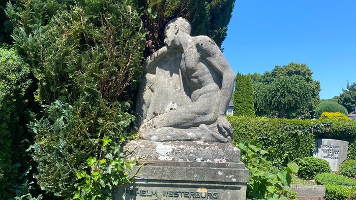 Grabmal mit Skulptur in parkähnlichem Friedhof